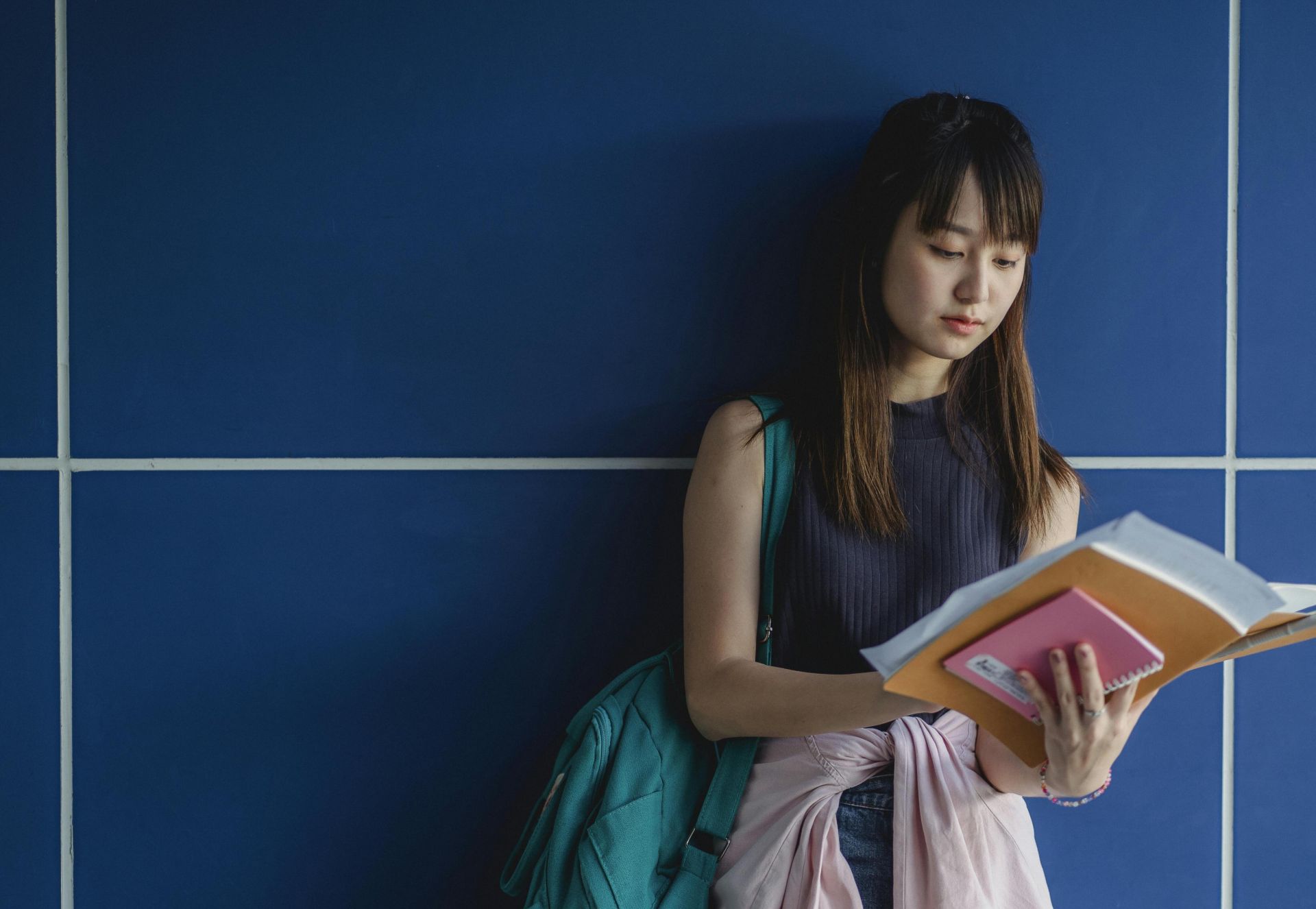Young attentive ethnic woman in casual apparel with exercise books preparing for exams in daytime